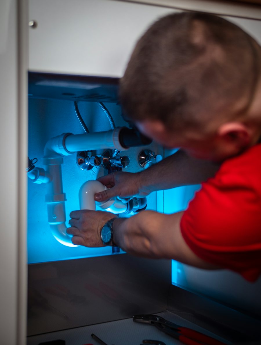 Plumber working on the drain pipes under a sink